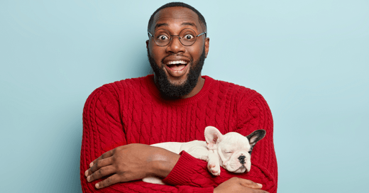 Smiling man holding a sleeping French Bulldog puppy in his arms