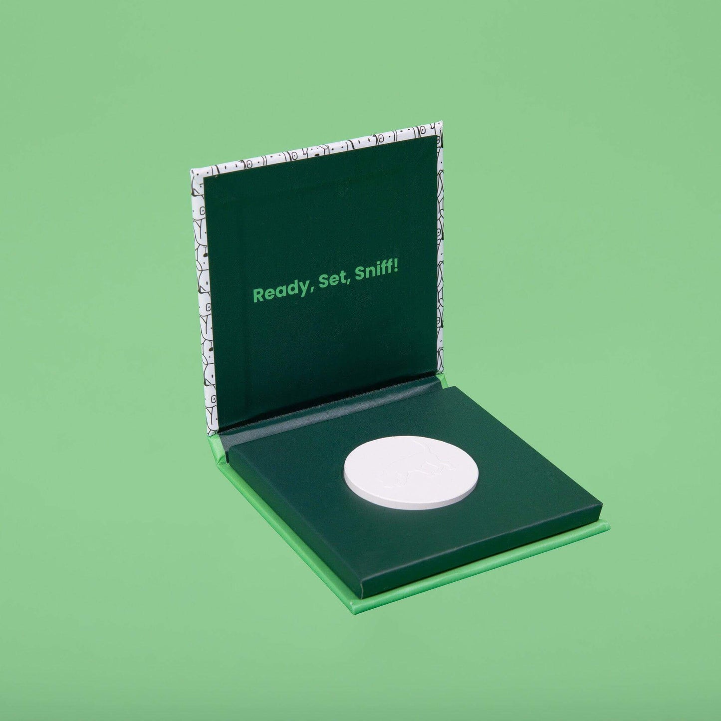 Open Mommy's Not Mad scent stone box showing the scent stone, 'Ready, Set, Sniff' text, and a dog tracking a scent on the stone.